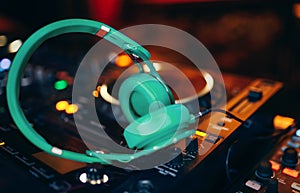 Closeup pair of aqua blue emerald green headphones for DJ.cd mp4 music deejay mixing desk music party in nightclub. Club console