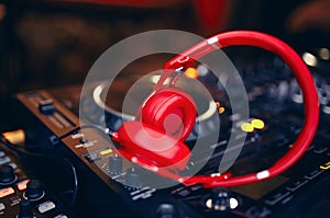 Closeup pair of Cheer red headphones for DJ.cd mp4 music deejay mixing desk music party in nightclub. Club console for experiments