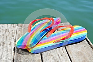 Rainbow flip-flops on a weathered dock