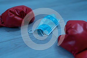 Red leather boxing gloves and a medical mask on a wooden background - pandemic sports concept photo