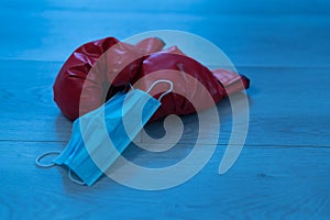 Red leather boxing gloves and a medical mask on a wooden background - pandemic sports concept photo