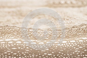 Closeup pale beige lace unwound on a white table