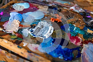 Closeup palette with paintbrush and palette-knife at studio or home background.