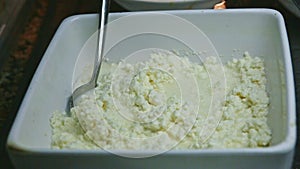 Closeup panorama at grainy fresh cottage cheese served in deep white bowl