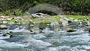 Closeup panorama at wide mountain river blue stream with big stone rapids