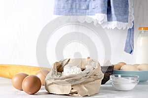 Closeup of paper bagfull of flour, eggs and salt- key ingredients for dough.Rural mood, grandmother`s kitchen