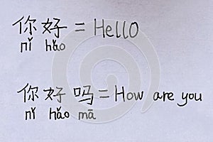 Closeup of paper handwritings homework in both Chinese with pinyin and English characters of Hello and How are you