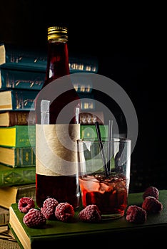 Closeup part of bottle and glass with craft raspberries alchol drink with berries around on library background