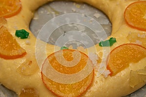 Closeup of a part of a raw roscon de reyes with candied fruit decoration