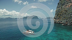 Closeup passenger boat at ocean bay with green cliff shore at aerial. Tropic seascape at sand beach