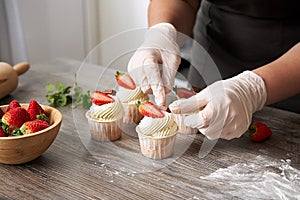 Closeup of a pastry chef decorating cupcakes