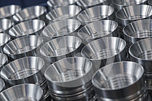 Closeup pattern of shiny circular precision stainless steel industrial machine parts arranged in rows on pallet. Steel