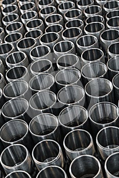 Closeup pattern of shiny circular precision stainless steel industrial machine parts arranged in rows on pallet. Steel