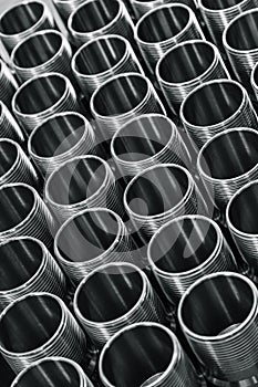 Closeup pattern of shiny circular precision stainless steel industrial machine parts arranged in rows. Steel products to