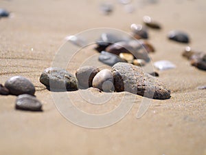 Closeup of pebble stones on sand on a beach