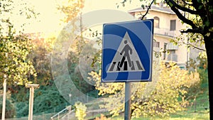 closeup of Pedestrian Crossing Sign Board. On the background, an autumn landscape of a small town.