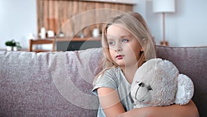 Closeup pensive little cute girl hugging teddy bear at home suffering loneliness lost parents