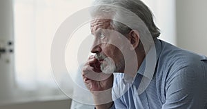 Closeup pensive older man sit on sofa staring into distance