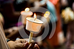 Closeup of people holding candle vigil in dark seeking hope