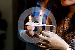 Closeup of people holding candle vigil in dark seeking hope