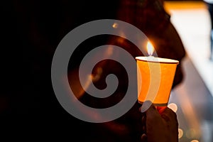 Closeup of people holding candle vigil in dark seeking hope