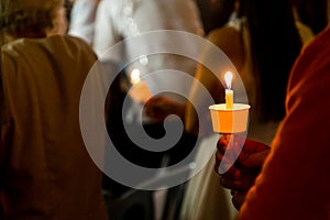 Closeup of people holding candle vigil in dark seeking hope