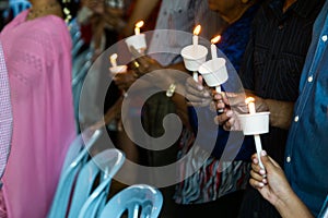 Closeup of people holding candle vigil in dark seeking hope