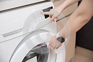 closeup people home house maid using front load washing machine touch press program button
