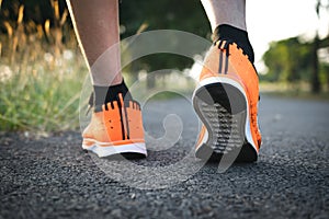 Closeup people walking with orange shoes on road in park for health concept.