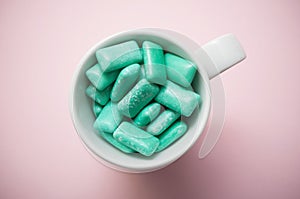 peppermint chewing gum in a white cup on pink backgro