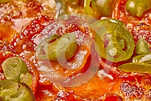 Closeup of pepperoni pizza with pickled jalapenos, cheese and tomato sauce