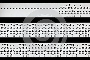 Closeup of perforated punched tape on black background