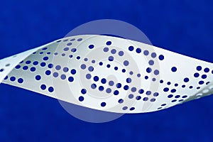 Closeup of perforated punched tape on blue background