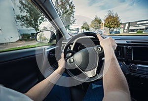 Closeup person hands on the steering wheel, confident driving car on the city streets