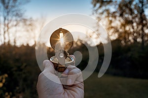 Closeup of a person holding a compass with sun shining through the hole with blurred background photo