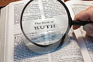 Closeup of a person holding a magnifier and reading the book of Ruth from the New Testament