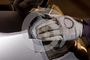 Closeup of a person placing tape on the headlights of a car in the garage