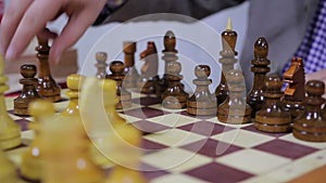 Closeup of person playing chess game on a wooden board in the gameroom