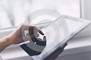 Closeup of a person pointing finger to a computer monitor with a blank screen blue against a background of window horizontal