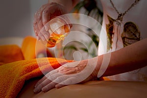 Closeup of a person pouring oil on a person's back during the massage