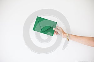 Closeup of a person's hand holding a green envelope on a white bacckground