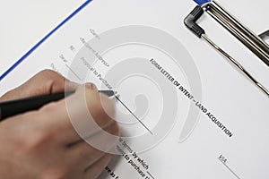 Closeup of a person signing a Form letter of intent for land acquisition photo