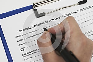 Closeup of a person signing a Standard contract for live performance by musicians