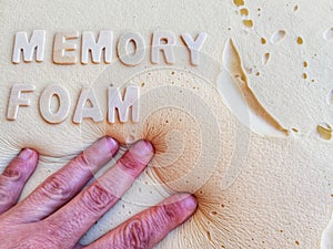 Closeup of a person touching a cushion with [MEMORY FOAM] written on it