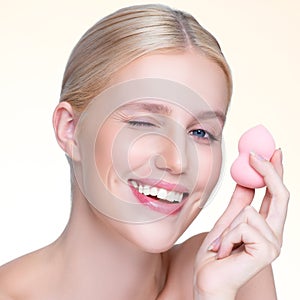 Closeup personable natural makeup woman using powder puff for facial makeup.