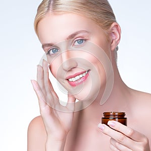 Closeup personable woman applying moisturizer cream on her face for perfect ski