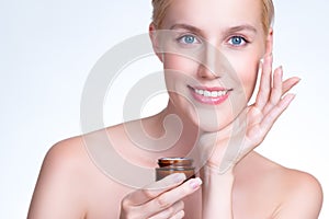 Closeup personable woman applying moisturizer cream on her face for perfect ski