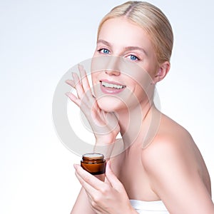 Closeup personable woman applying moisturizer cream on her face for perfect ski