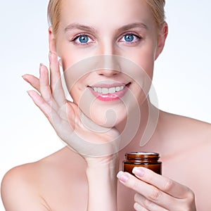 Closeup personable woman applying moisturizer cream on her face for perfect ski