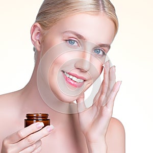 Closeup personable woman applying moisturizer cream on her face for perfect ski